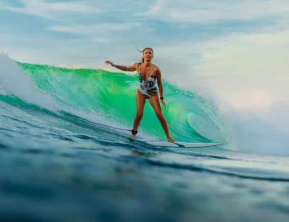 A woman in a bikini gracefully rides a wave on a surfboard, showcasing her surfing skills and enjoying the thrill of the ocean.