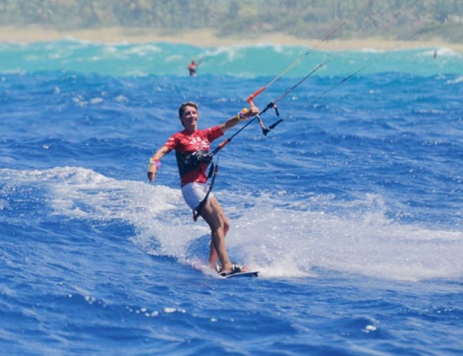 A woman kiteboarding on ocean waves, skillfully maneuvering the kite and gliding across the water.