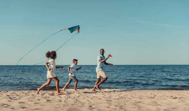 Man holding a kite, with the two kids running