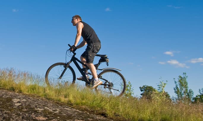 Mountain biking activity: A man riding a bike on a grassy hill.
