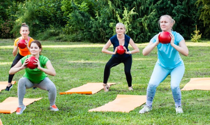 Group of young women doing exercises with kettlebells.