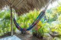 A hammock hanging in the shade of a hut, providing a relaxing spot to rest and enjoy the tranquil surroundings.